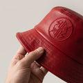 Photorealistic product detail photograph for Nothing But Goodz. Intimate close-up of the red butter-soft leather bucket 